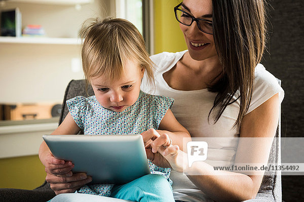 Mutter lehrt Tochter  das digitale Tablett zu Hause zu benutzen.