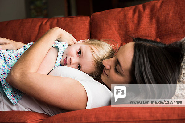 Mutter umarmt Tochter auf Sofa