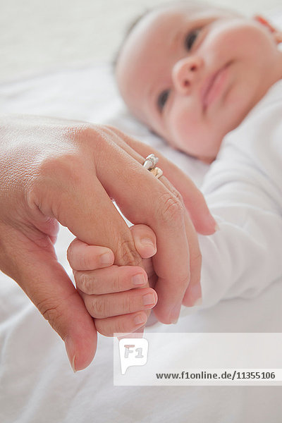 Mütter halten Baby Jungen an der Hand
