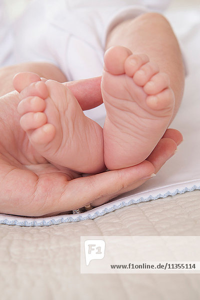 Mütter halten die Hand Baby Jungen Füße
