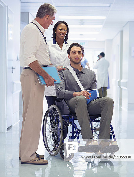 Doctor consulting with man in wheelchair with arm sling