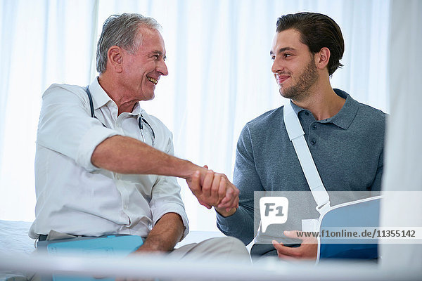 Doctor shaking hands with man in arm sling