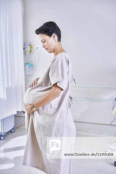 Side view of pregnant woman wearing hospital gown