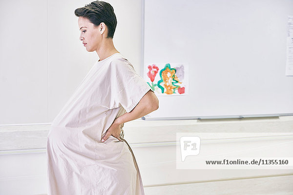 Seitenansicht einer schwangeren Frau im Krankenhauskittel