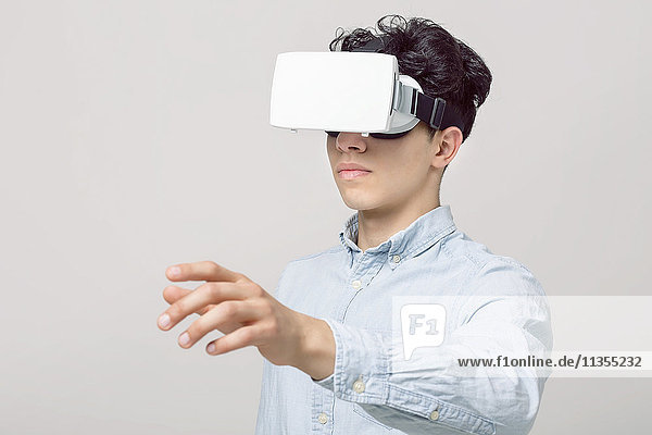 Junger Mann mit Virtual-Reality-Headset  der den Arm ausstreckt