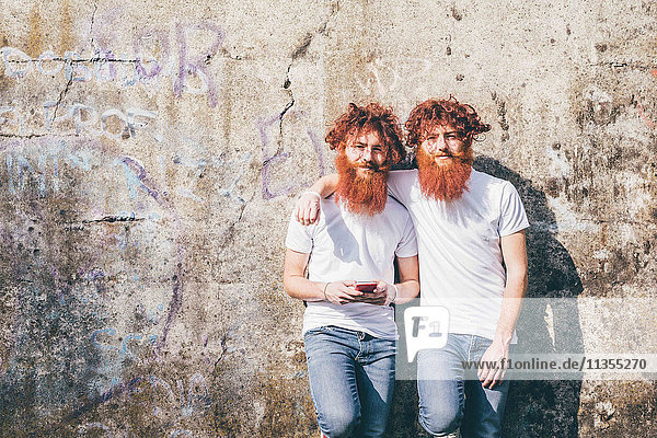 Porträt von jungen männlichen Hipster-Zwillingen mit roten Bärten vor der Wand stehend