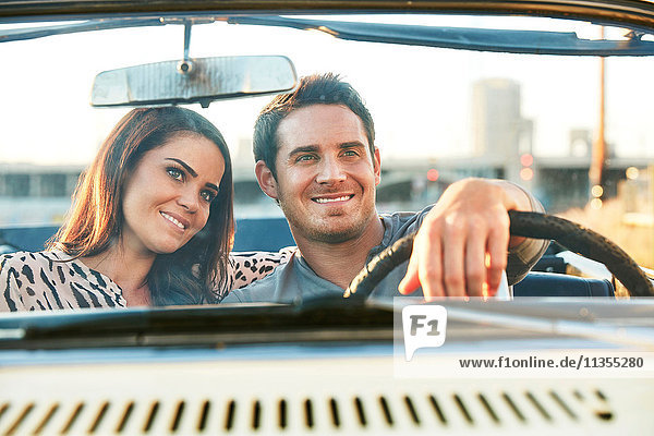 View through windscreen of couple in convertible car smiling  Los Angeles  California  USA