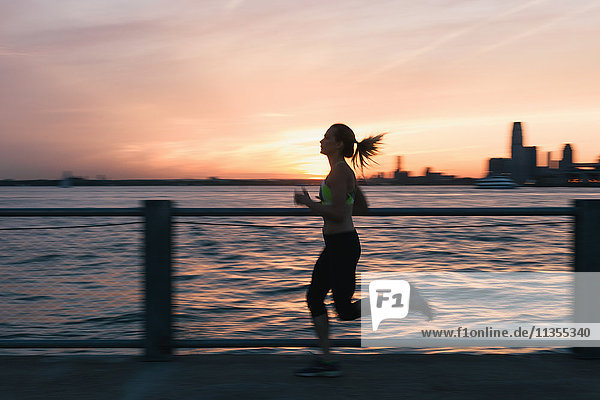 Junge Frau die im Freien trainiert und am Wasser läuft Brooklyn New York USA