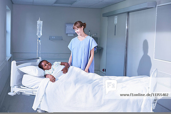Krankenschwester im Gespräch mit Patientin im Bett auf der Kinderstation des Krankenhauses