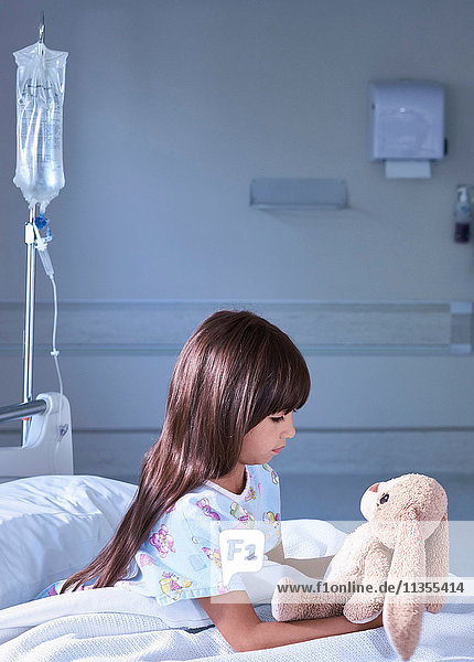 Patientin  die einen Spielzeughasen auf der Kinderstation eines Krankenhauses anstarrt