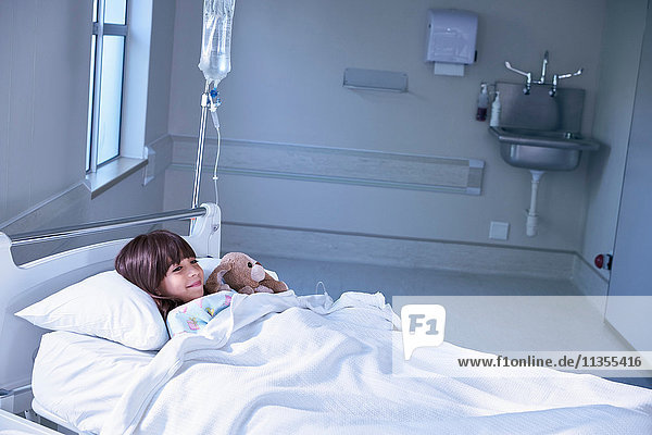 Patientin im Bett umarmt Spielzeugkaninchen auf Krankenhaus-Kinderstation