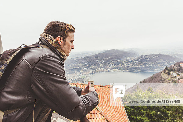 Young man looking out from roof terrace at misty Lake Como  Italy