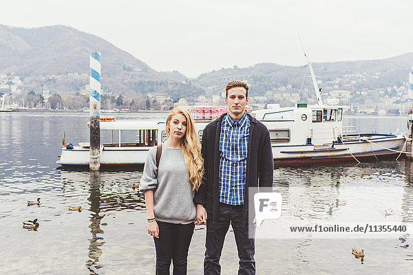 Portrait of young couple holding hands at misty Lake Como  Italy