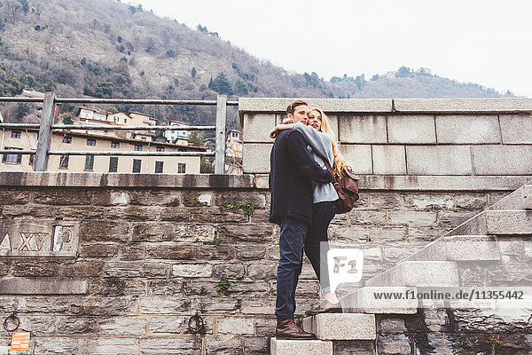 Young couple hugging harbour wall steps  Lake Como  Italy