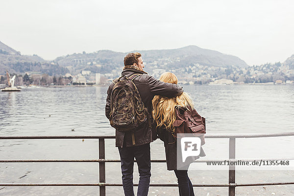 Rückansicht eines jungen Paares mit Blick auf das Seeufer  Comer See  Italien
