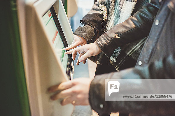 Junges Paar kauft Zugfahrkarten am Touchscreen-Fahrkartenautomaten