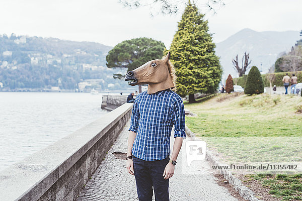 Portrait of man wearing horse mask looking out at Lake Como  Italy