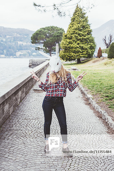 Portrait of woman wearing rabbit mask making peace sign  Lake Como  Italy