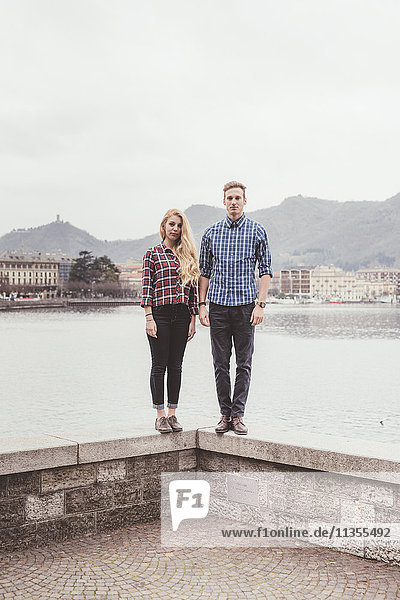 Portrait of young couple standing on harbour wall  Lake Como  Italy