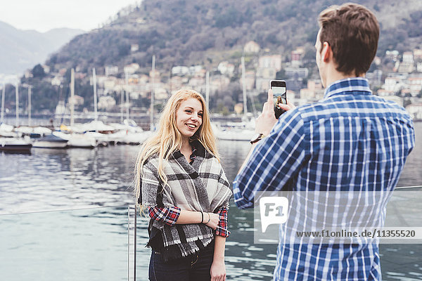 Young man on waterfront photographing girlfriend  Lake Como  Italy