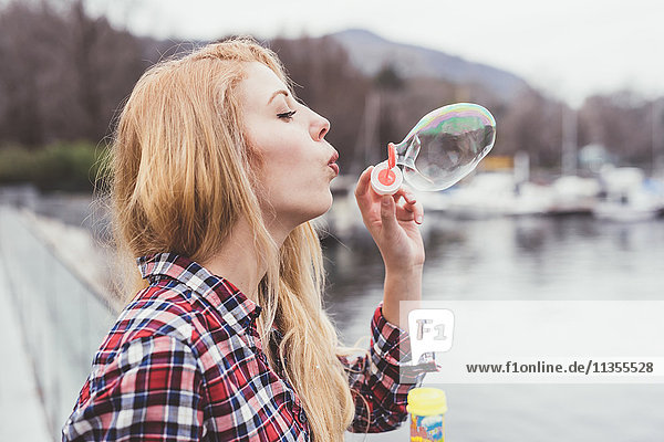 Young woman on waterfront blowing bubbles  Lake Como  Italy