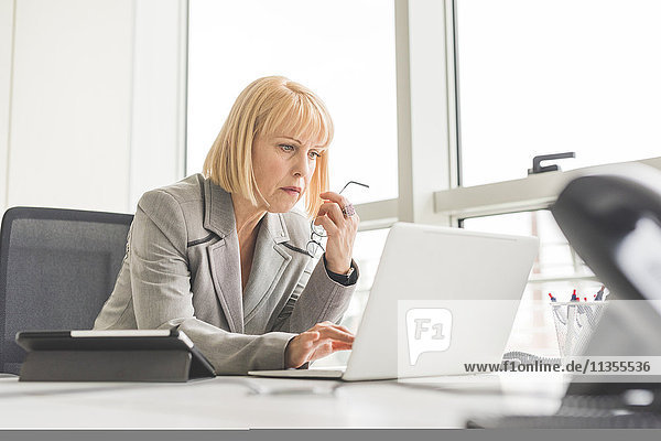 Reife Geschäftsfrau liest Update auf Office-Laptop