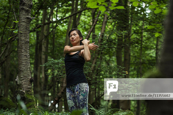 Mittlere erwachsene Frau beim Waldtraining  Stretching