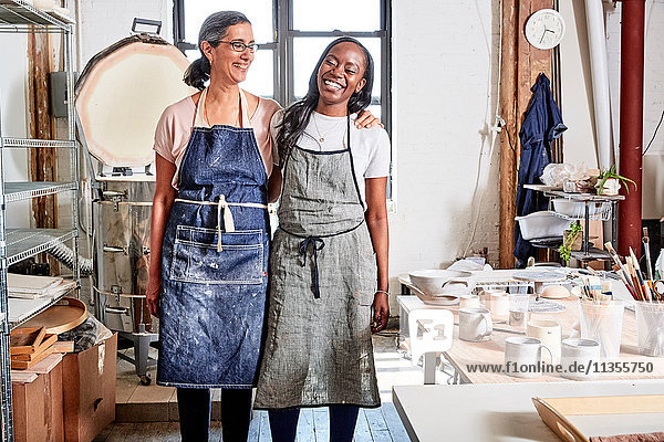 Potters in workshop wearing aprons smiling