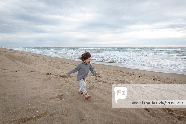 Girl running on beach by ocean