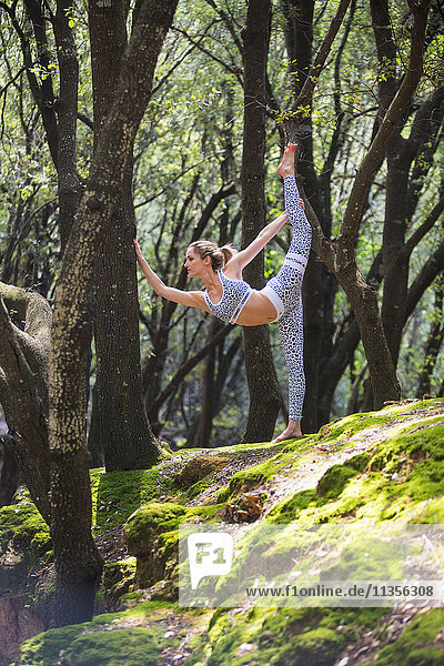 Woman on rock standing on one leg stretching
