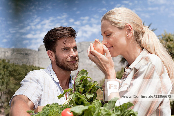 Mature couple in garden  woman smelling onion