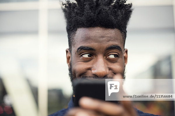 Low angle view of happy man using smart phone while looking away