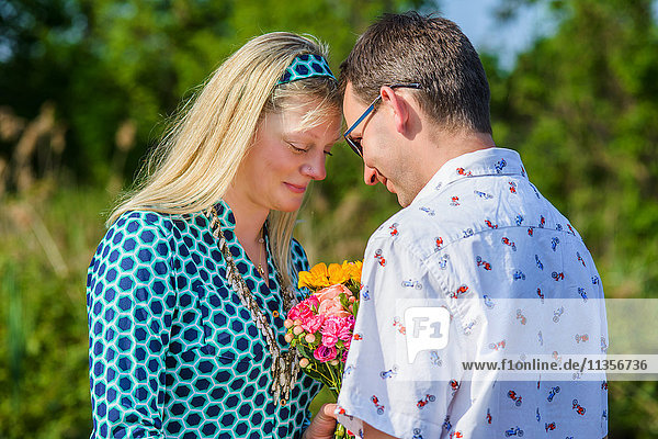Couple face to face holding flowers