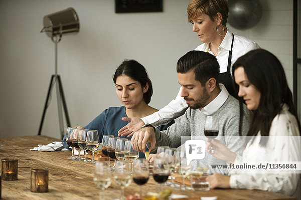 Geschäftsleute  die am Tisch sitzen und verschiedene Weine probieren.