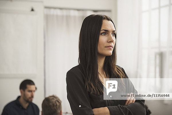 Thoughtful businesswoman with arms crossed in office