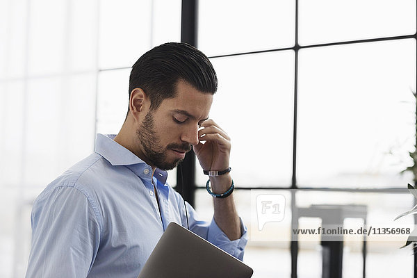 Businessman listening music while standing in office