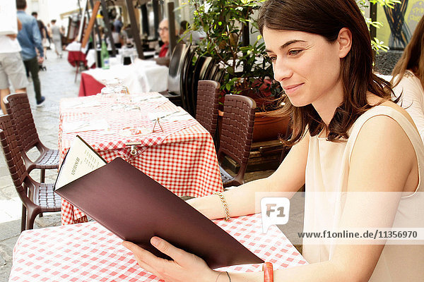 Woman at sidewalk cafe reading menu  Milan  Italy