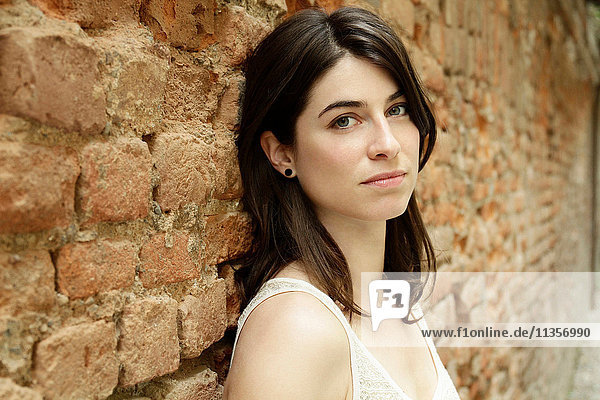 Portrait of beautiful Italian woman leaning against brick wall  Milan  Italy