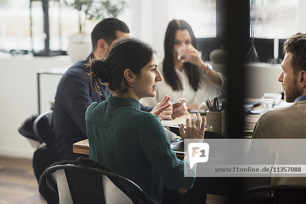 Businesswoman discussing with colleagues during meeting in office