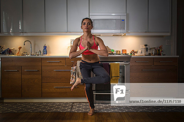 Junge Frau in der Küche  in Yogastellung
