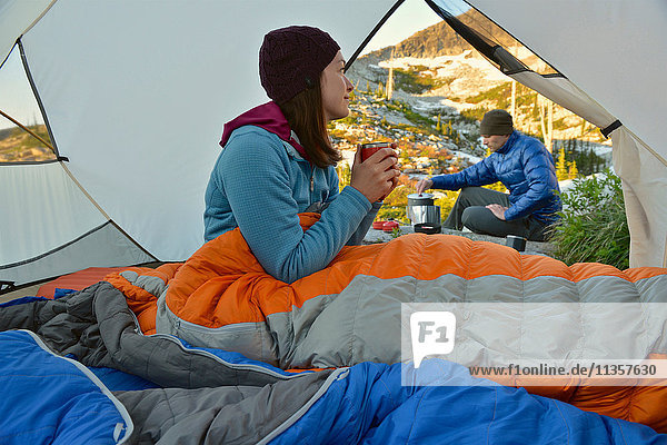 Mann bereitet das Frühstück für seine Freundin im Zelt am Fault Lake  Selkirk Mountains  Idaho  vor