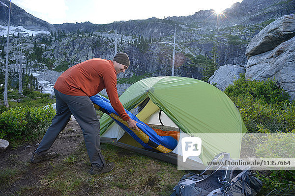 Mann legt Schlafsack bei Sonnenuntergang ins Zelt  Fault Lake  Selkirk Mountains  Idaho