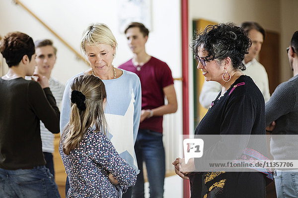 Mother talking to daughter against friends and family standing in living room