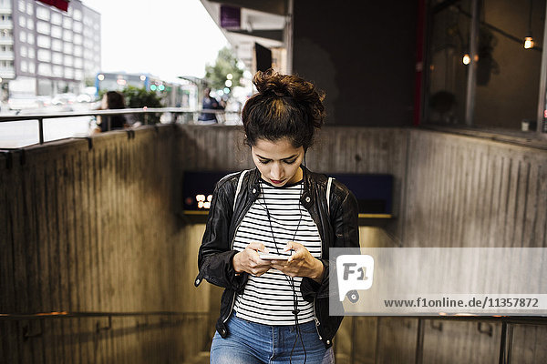 Woman using smart phone while walking at subway station