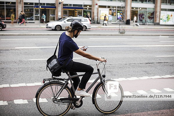 Volle Länge des Mannes beim Radfahren auf der Stadtstraße