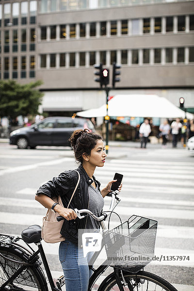 Seitenansicht der Frau mit Fahrradhalterung beim Stehen auf dem Zebrastreifen in der Stadt
