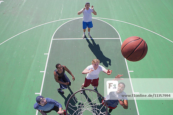 Gruppe von männlichen Freunden beim Basketballspielen auf dem Aussenplatz  erhöhte Ansicht