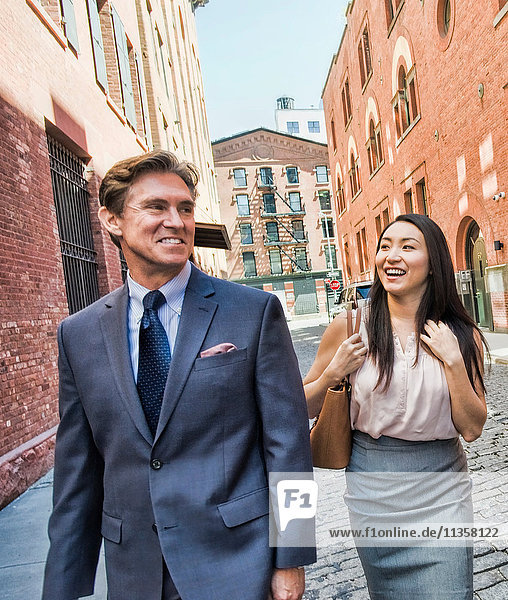 Businessman and woman walking together in street  smiling
