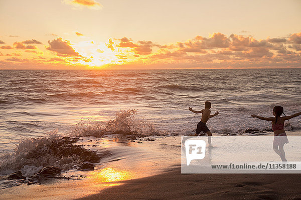 Girl and brother running on beach at sunrise  Blowing Rocks Preserve  Jupiter Island  Florida  USA