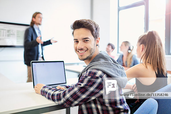 Porträt eines jungen männlichen Studenten mit Laptop im Klassenzimmer einer Hochschule